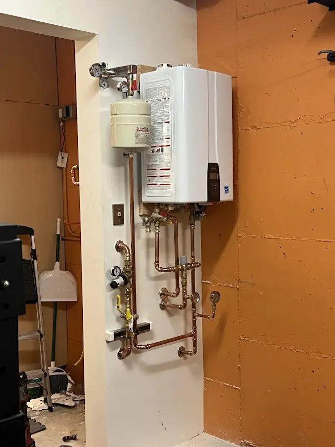 Plumbing technician inspecting water heater connections in Riley